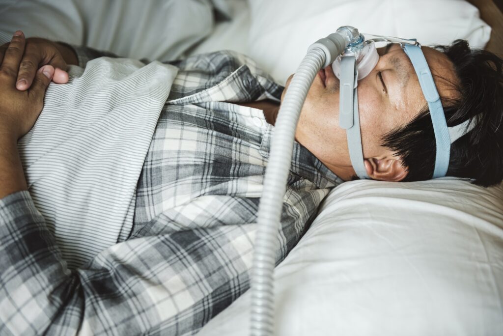 A man sleeping with anti snoring chin strap