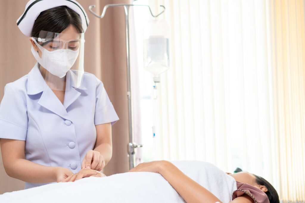 Asian nurse applying an IV drip to a patient